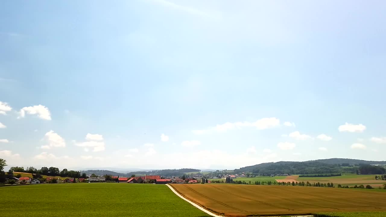 Picturesque rural landscape with fields, village, and blue sky