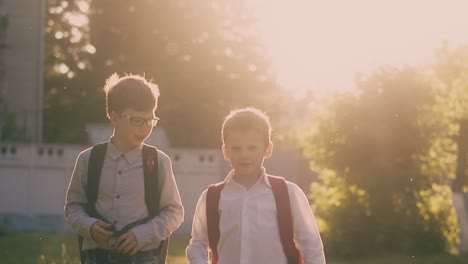 Niño-Lanza-Papel-Caminando-Con-Un-Compañero-De-Escuela-En-Cámara-Lenta-Del-Parque