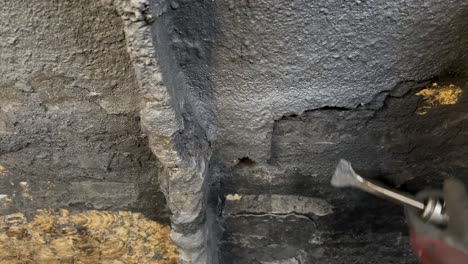primer plano de un cincel de aire que se usa contra una pared en el interior de un tanque comercial para eliminar la escoria de la capa de sellado