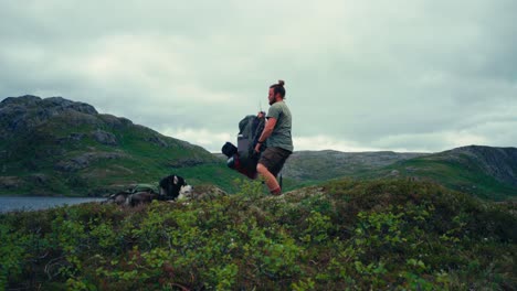 male backpacker with alaskan malamute packing up on shore of palvatnet lake in osen, norway