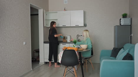 young girl getting a bowl of different size from kitchen shelf to give to sibling seated at table while they prepare for breakfast in cozy home kitchen, family interaction, morning routine