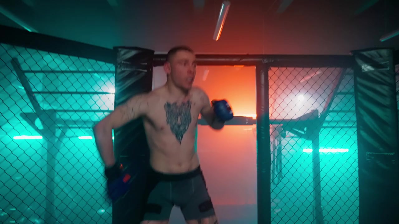 Boxeador musculoso haciendo boxeo de sombra en una dramática jaula de MMA iluminada con neón.