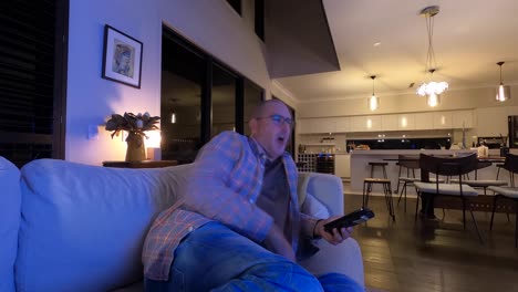un hombre maduro que mira televisión revisa su teléfono, bosteza y se queda dormido