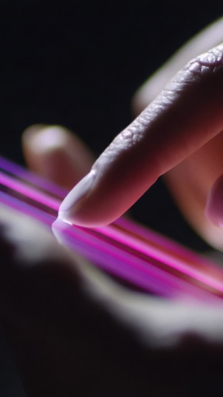 A close-up view of a hand delicately interacting with vibrant, glowing lines on a touchscreen, showcasing technology's seamless integration with human touch