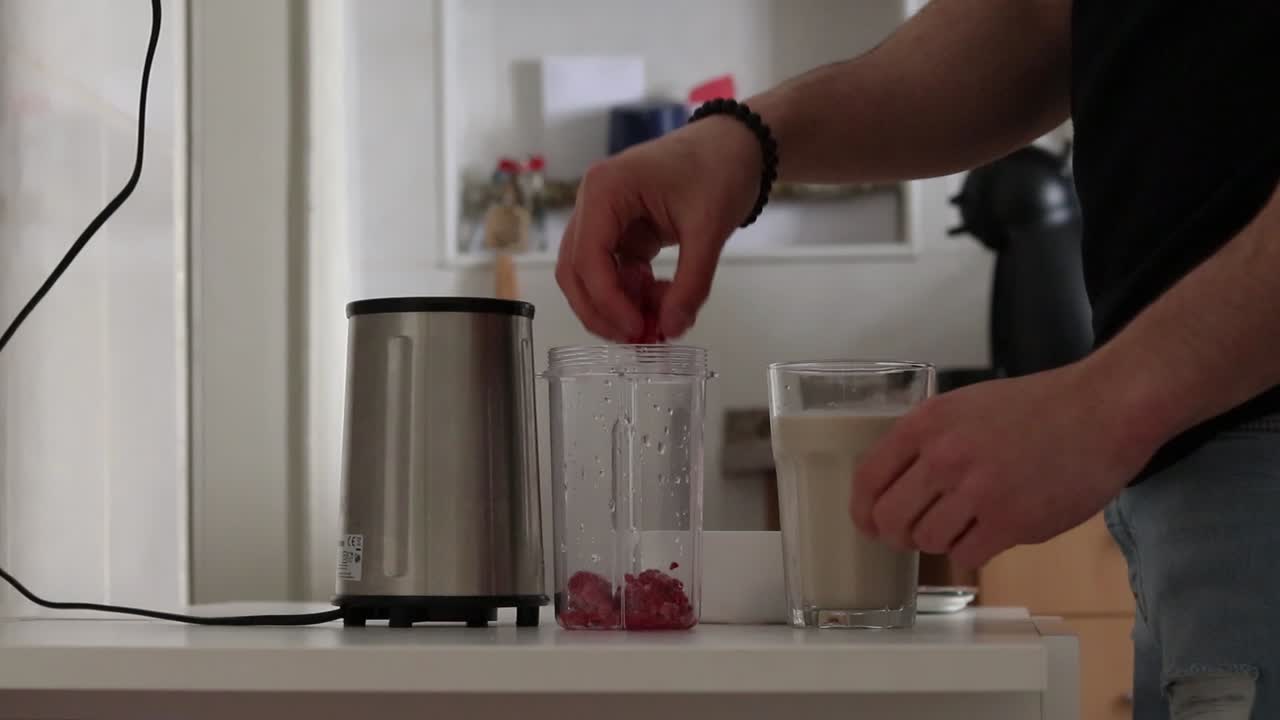 Man making a milkshake with frozen raspberries and oat milk, part one.