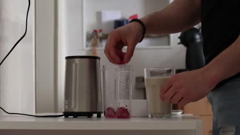 man making a milkshake with frozen raspberries and oat milk, part one.
