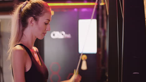 Determined-Young-Woman-Using-Cable-Machine-During-Workout-At-Fitness-Club