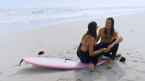 surfer couple talking on the beach 4k