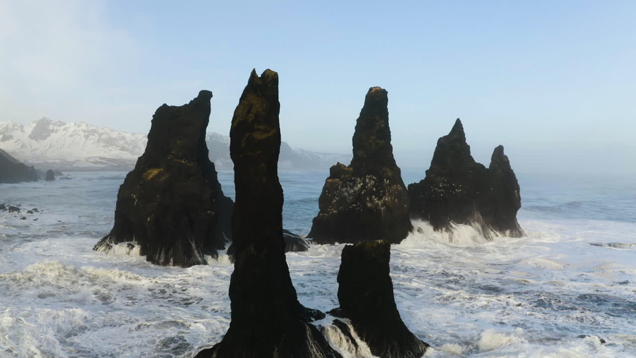 disparo de un dron volando a través de las rocas de reynisdrangar, en la costa de islandia invernal