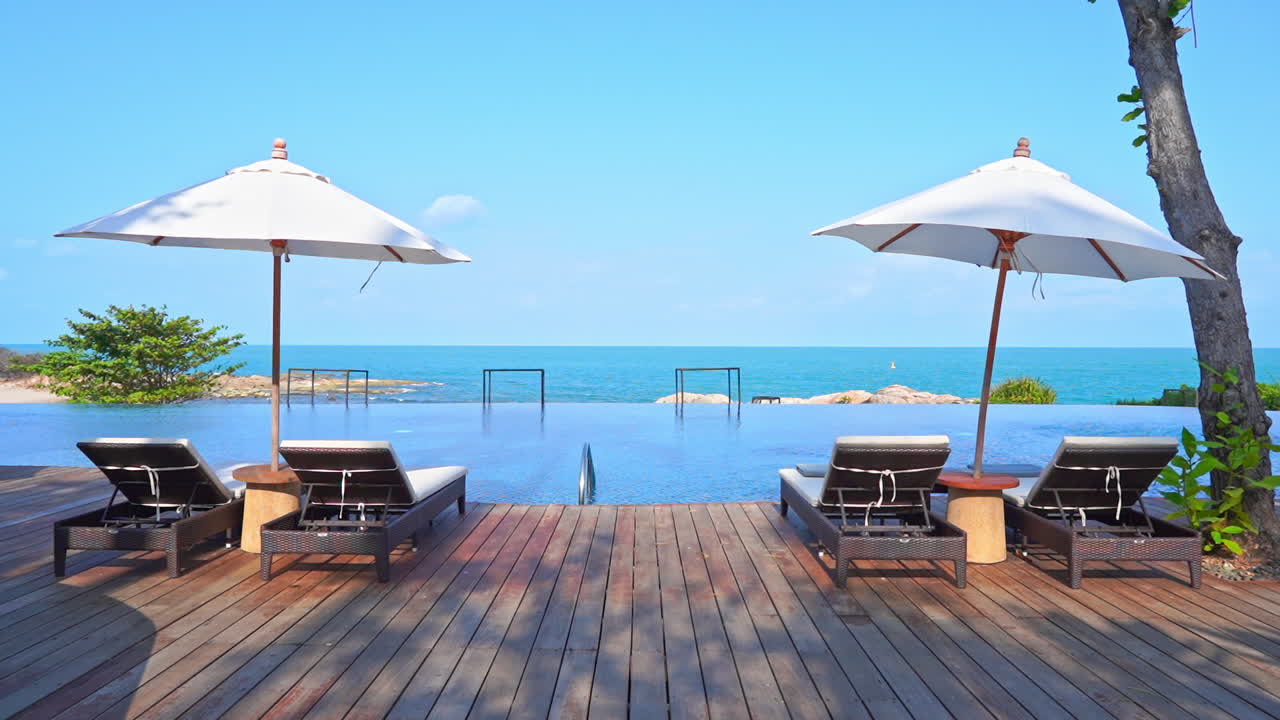 빈 일광욕 의자 두 세트가 리조트 수영장 가장자리에 있습니다.