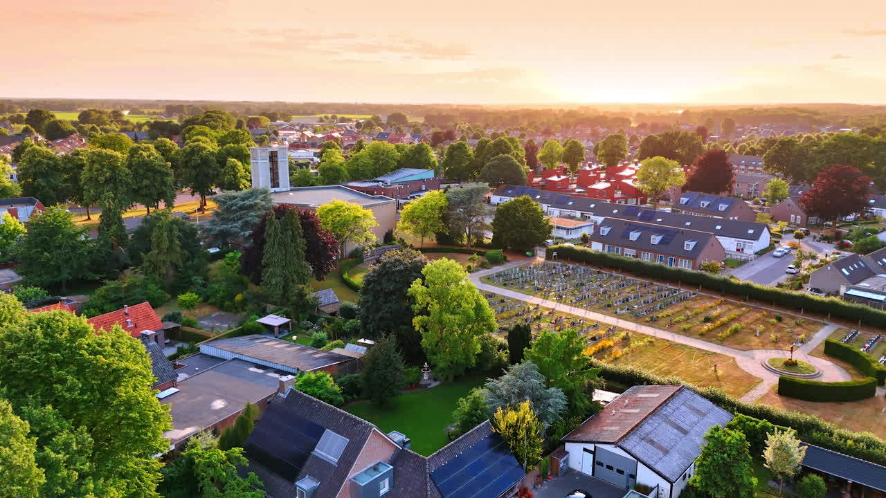 Lush greenery of the town from drone footage. Approaching church and cemetery in Overloon, the Netherlands