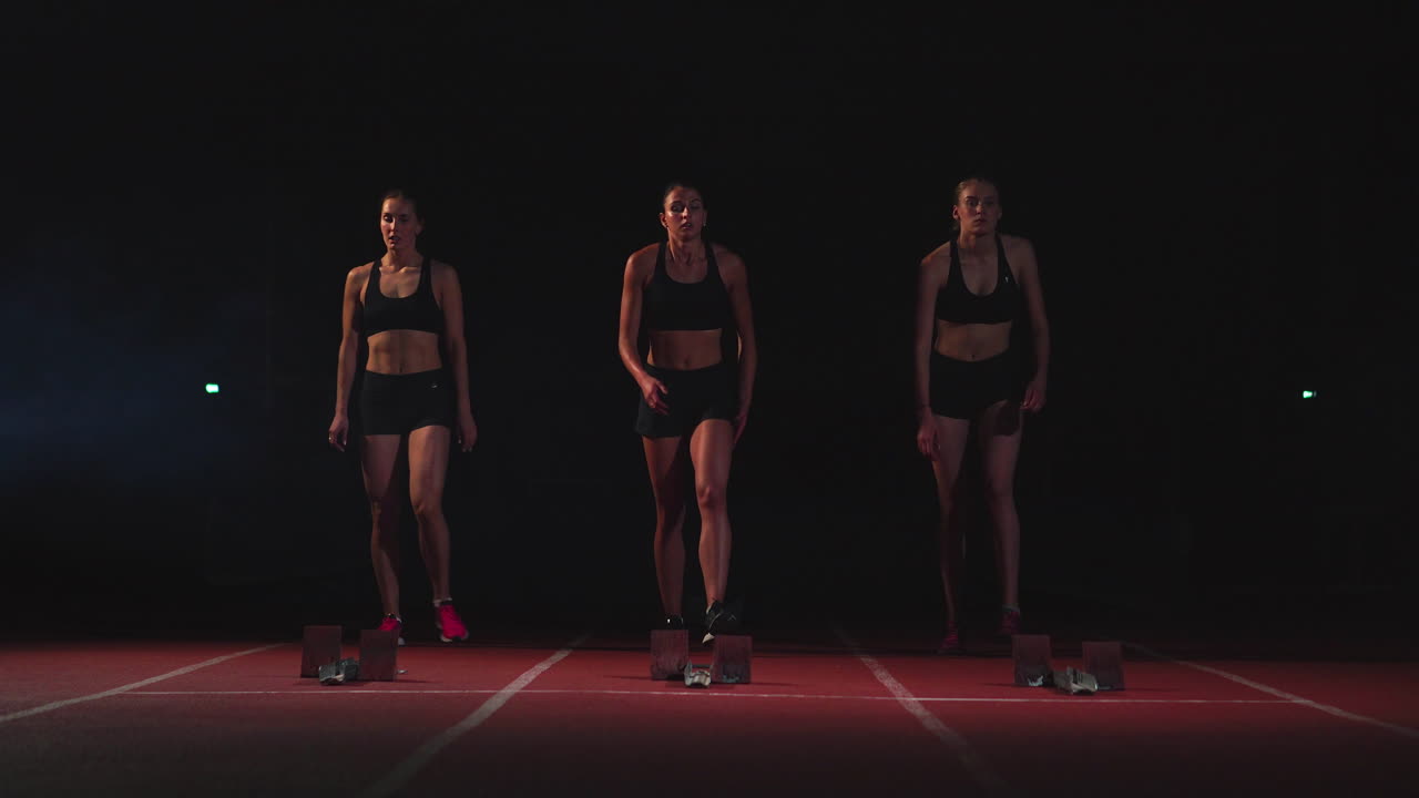 tres atletas chicas en el inicio preparándose para la carrera y comenzando en la cinta de correr.