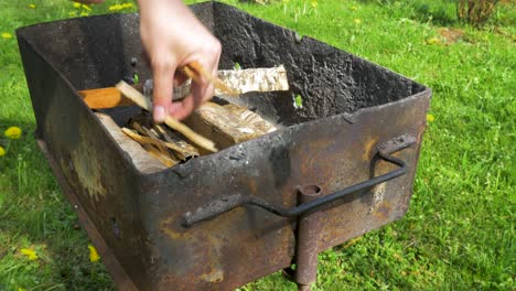 young man laying down wood log and prepares rusty grill for baking and bbq, medium close up shot