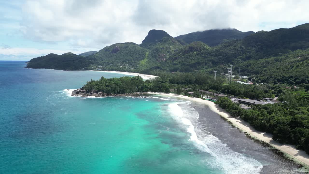 Aerial view of Mahe Island's pristine beach and coastline in Seychelles, showcasing lush greenery, azure waves, and white sand, reflecting tropical paradise and serenity. orbit motion