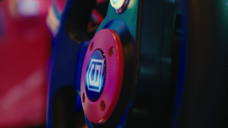 close up of hands young kid child holding a steering wheel controlling a video games car playing in game room