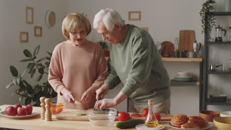 senior couple cooking dinner and chatting in kitchen