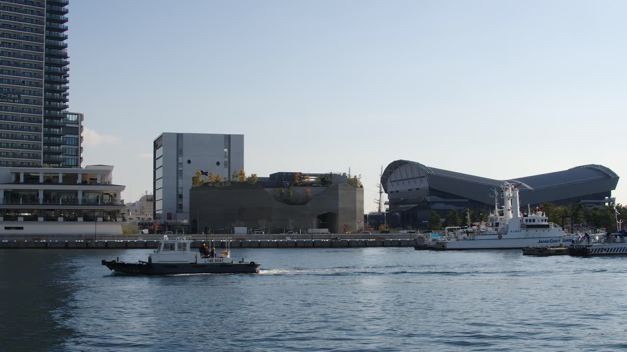 Harbor line boat enters Kobe port past Coast Guard waterfront marina