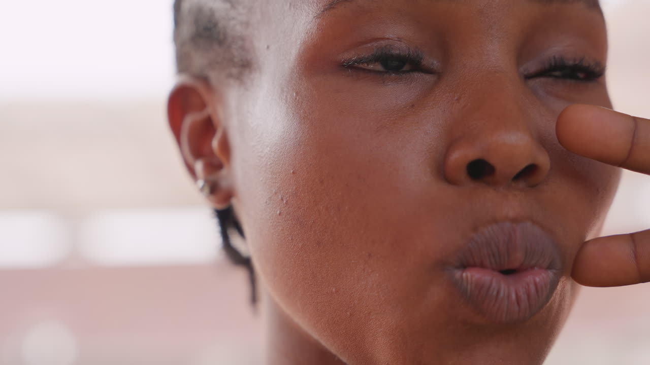En kvindelig influencer med mørk hudfarve laver kyssemund tæt på, strålende hud med dug, flettet hår, legende smil og kindbevægelse, en stemning af hudpleje- og skønhedsindhold til trendvideoer på sociale medier.