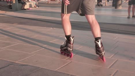 slow motion, close up on person's feet roller blading on pavement during golden hour