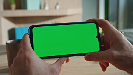 student browsing content green screen smartphone at home close up. man hands