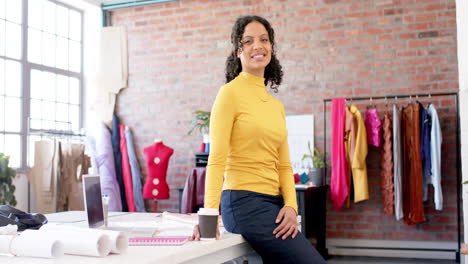 Portrait-of-happy-biracial-female-fashion-designer-crossing-arms-in-studio,-slow-motion