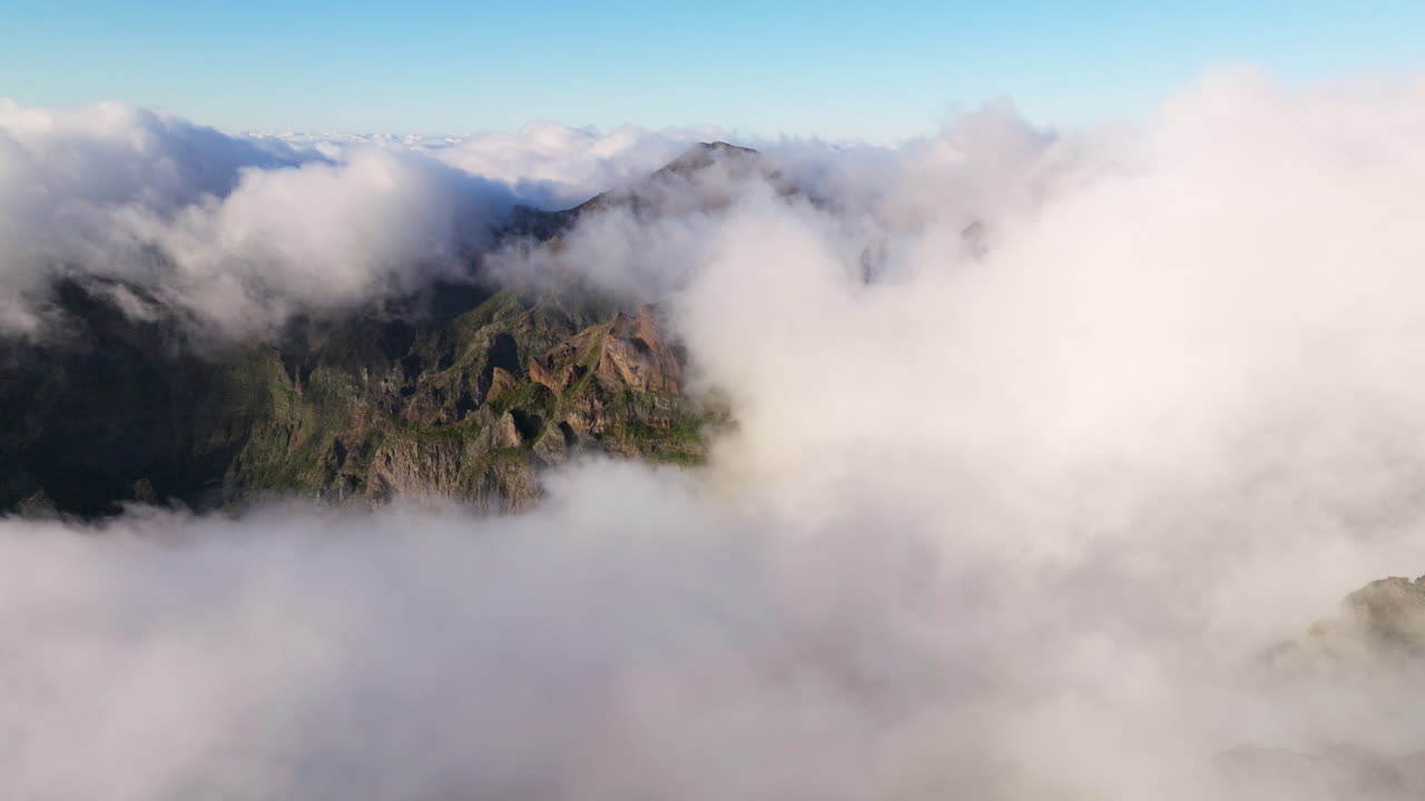구름은 포르투갈 마데이라 섬의 일출에 피코 두 아리에이로의 산봉우리를 둘러싸고 있습니다