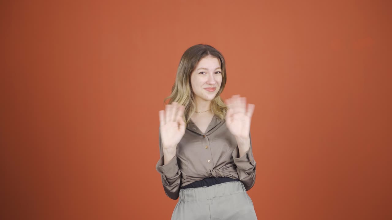 행복한 젊은 여성이 카메라를 향해 손을 흔들고 있습니다.