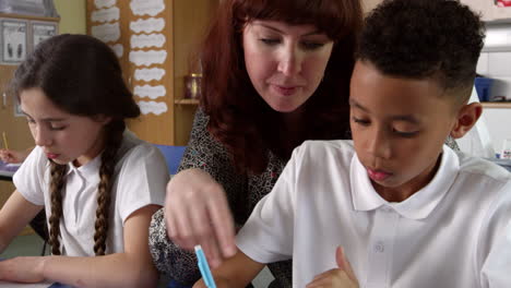 teacher helps male pupil with work in classroom shot on r3d