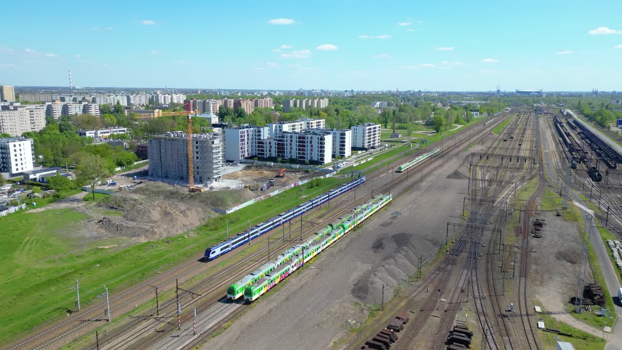 живописный воздушный снимок пассажирского поезда, движущегося к закату на железнодорожных путях, окруженных деревьями над городским пейзажем вперед