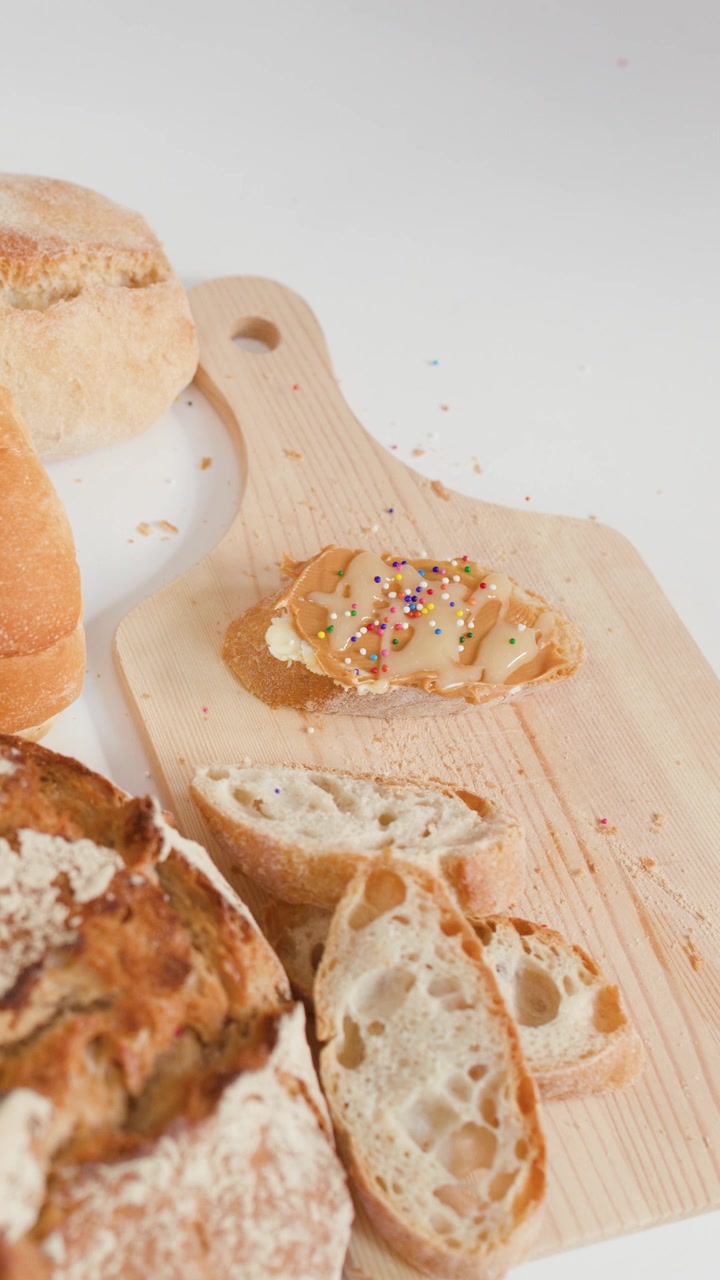 Codette colorate che cadono su toast con burro d'arachidi su un tagliere di legno