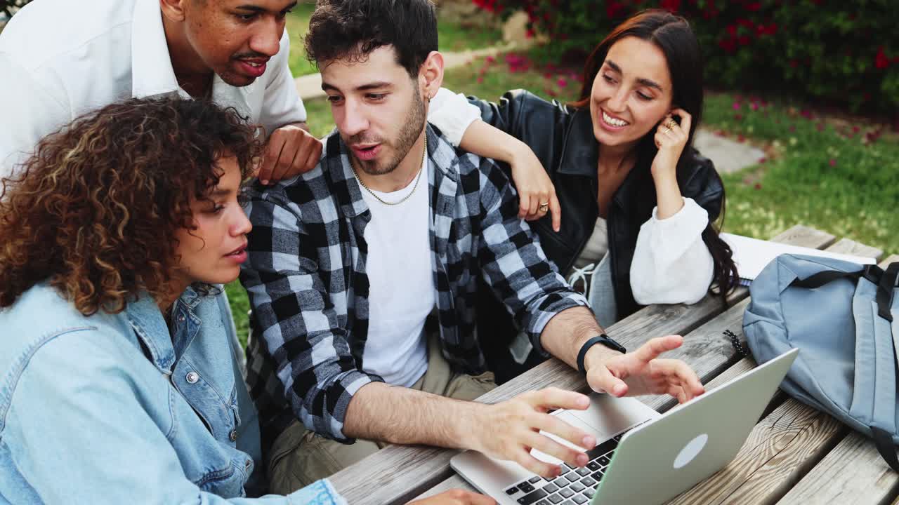 Grupo diverso de jóvenes adultos colaborando en un portátil al aire libre