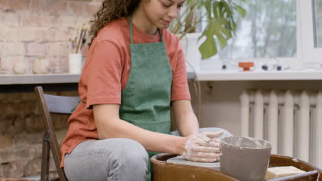 clerk woman modeling ceramic piece on a potter wheel in a workshop