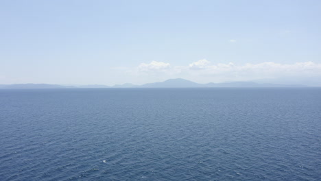 blue background aerial flight over calm aegean sea on coast of greece