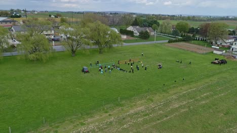 a drone view of amish farmlands and homesteads and approaching amish teens playing volleyball on a sunny day