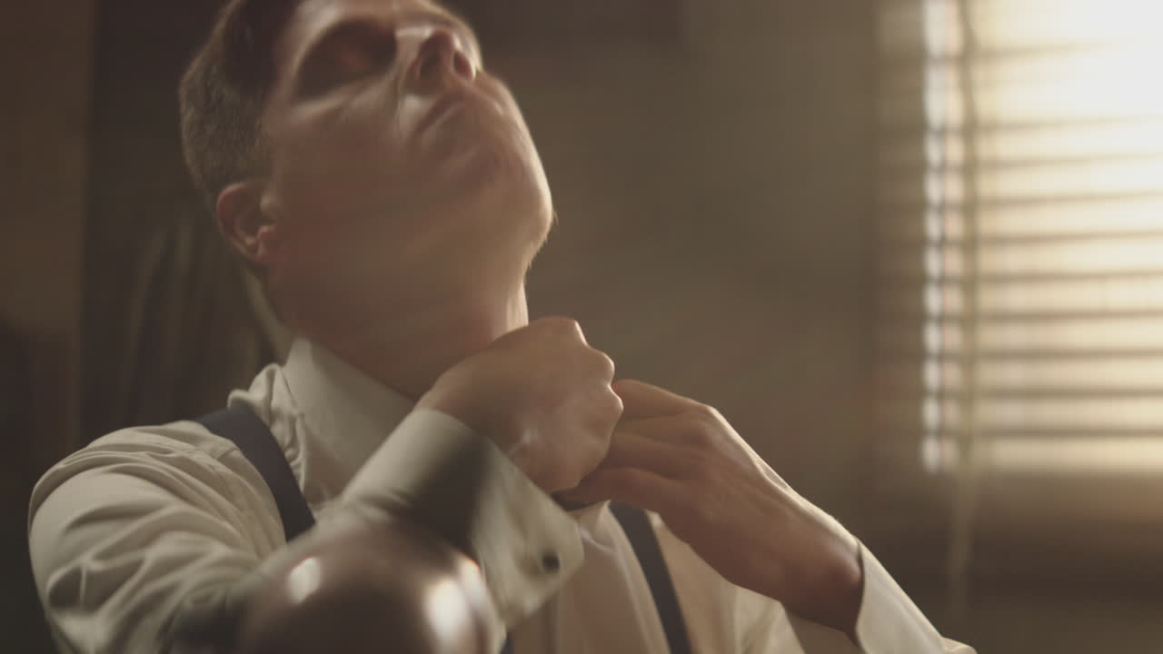 남자가 레트로 세팅에서 목걸이를 조정하고 있습니다.