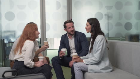 a working group of two businesswomen and two businessmen chatting relaxedly with some coffees in the lobby of an airport before a business trip 4