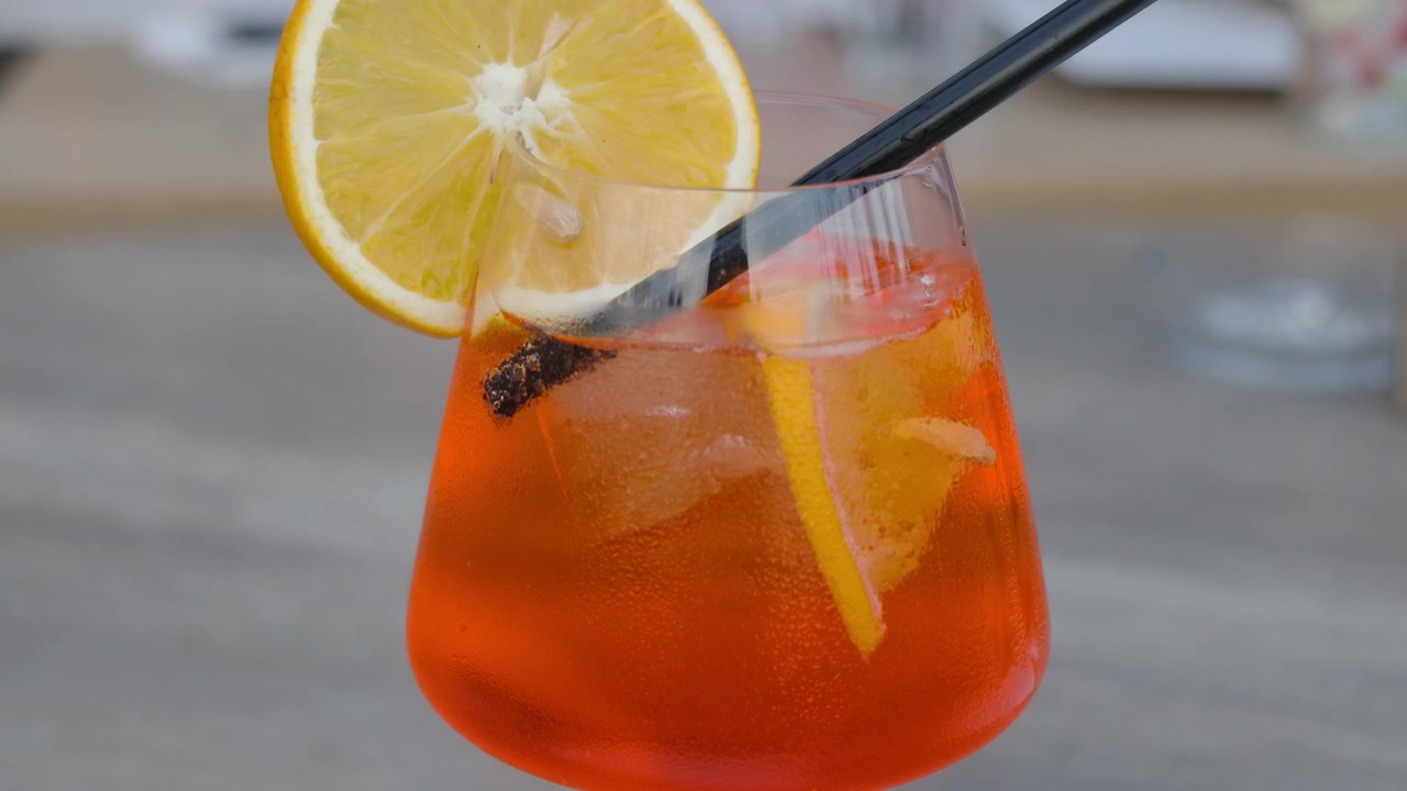 Primo piano di un cocktail spritz all'arancia con ghiaccio, una fetta d'arancia e condensa sul bicchiere