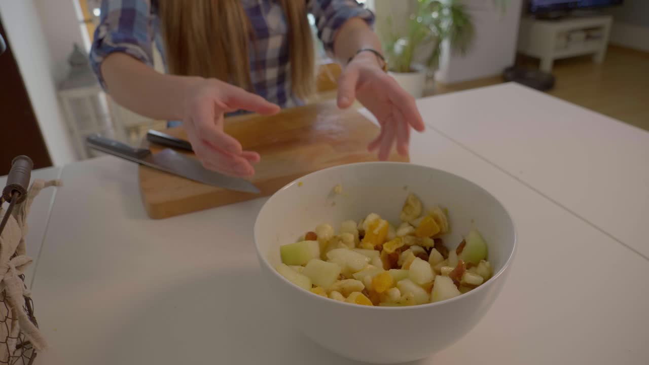 esta es una toma en cámara lenta de 4k 60fps de una niña moviendo un tazón blanco con ensalada de frutas