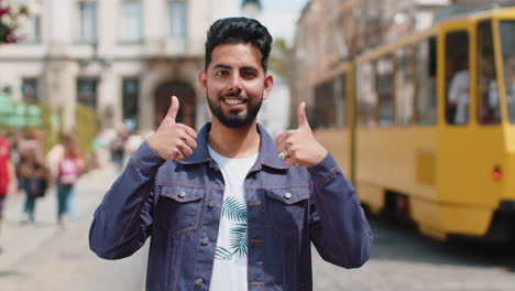 Young-man-showing-thumbs-up,-like-sign-positive-something-good-positive-feedback-in-city-street