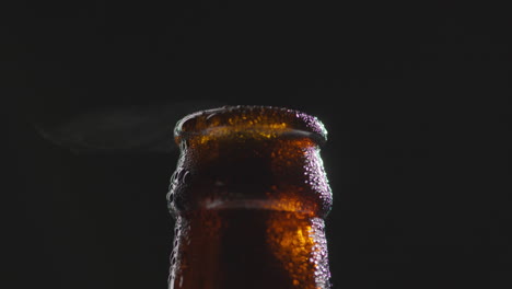 cierre de gotas de condensación en el cuello de una botella giratoria de cerveza fría o bebida gaseosa con vapor de agua después de la apertura