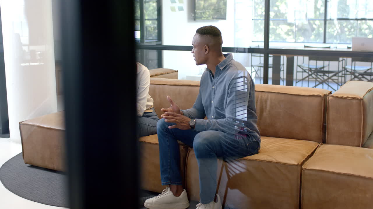 Discussing work, business colleagues sitting on couch in modern office setting