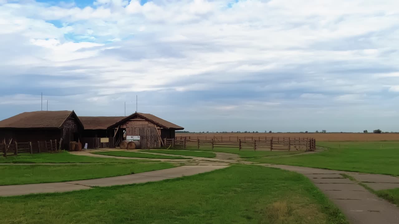 Idyllic timelapse from the Hortobagy National Park with an empty wooden barn and endless grassland on a cloudy day in Hungary.