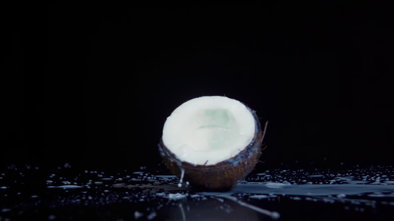 Coconut broken in slow motion on black background