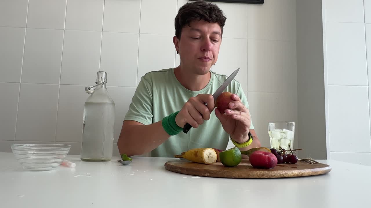 Uomo che Mangia e Prepara Frutta Fresca in una Cucina Luminosa