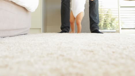 Father-helping-baby-to-walk-across-rug