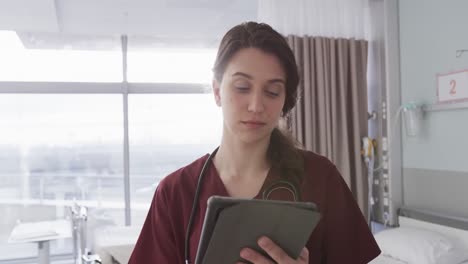 retrato de una feliz mujer médica caucásica usando una tableta en una habitación del hospital, en cámara lenta