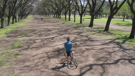 cyclist standing with bike and using map on phone in the park