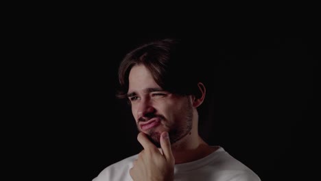 trendy young man thinking and rubbing chin, close, black background