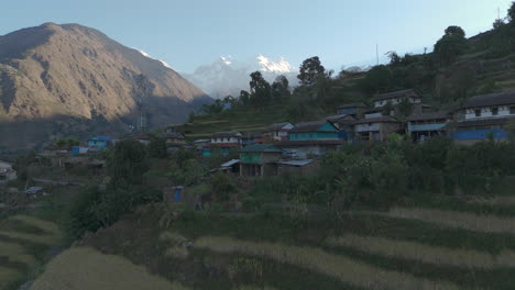 Drone-shot-of-an-aesthetic-village-in-Lamjung,-Nepal,-featuring-traditional-housing-and-architecture-beautiful-tourist-place-with-a-healthy-environment,-showing-the-Himalayas,-terrains,-and-hills