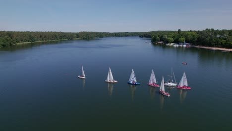 Sailboats-sail-on-a-lake,-distant-drone-parallax-shot